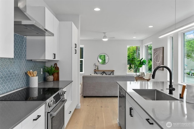 1327 N 185th St Unit A, Shoreline, WA 98133 - kitchen with appliances with stainless steel finishes, wall chimney range hood, light wood-style floors, decorative backsplash, and white cabinets