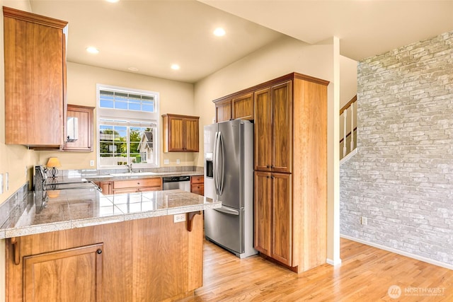 1725 Harrison Pl Unit 104, Lynden, WA 98264 - kitchen with stainless steel appliances, tile counters, brown cabinetry, light wood finished floors, and a peninsula
