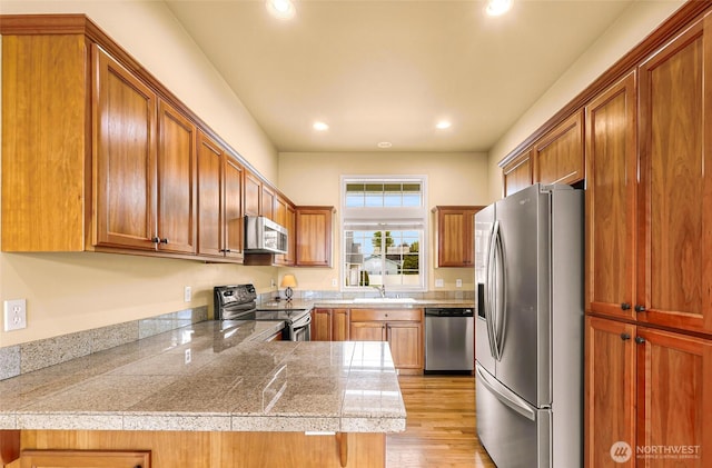 1725 Harrison Pl Unit 104, Lynden, WA 98264 - kitchen with appliances with stainless steel finishes, tile counters, recessed lighting, light wood-type flooring, and brown cabinets