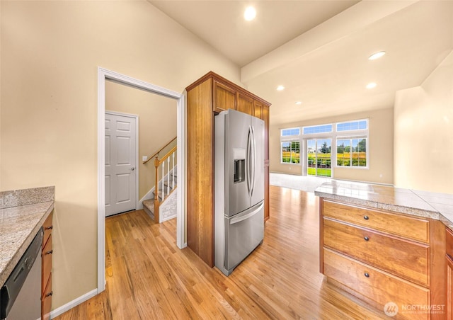 1725 Harrison Pl Unit 104, Lynden, WA 98264 - kitchen with appliances with stainless steel finishes, light wood finished floors, brown cabinetry, recessed lighting, and tile countertops