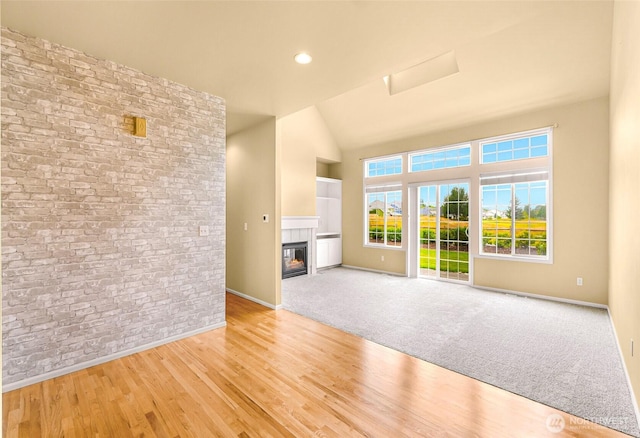 1725 Harrison Pl Unit 104, Lynden, WA 98264 - unfurnished living room with light wood finished floors, a glass covered fireplace, high vaulted ceiling, and attic access