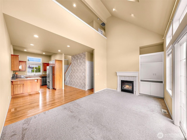 1725 Harrison Pl Unit 104, Lynden, WA 98264 - unfurnished living room featuring light colored carpet, a fireplace, recessed lighting, stairs, and high vaulted ceiling