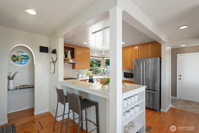 9423 45th Ave SW, Seattle, WA 98136 - kitchen featuring appliances with stainless steel finishes, under cabinet range hood, light countertops, light wood-style floors, and recessed lighting