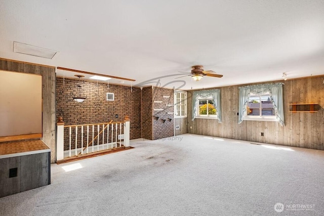 1727 E 64th St, Tacoma, WA 98404 - unfurnished living room featuring brick wall, carpet floors, wood walls, a ceiling fan, and attic access