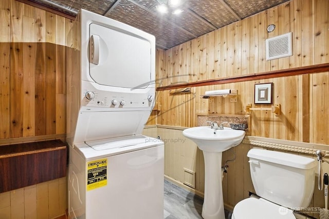 1727 E 64th St, Tacoma, WA 98404 - bathroom with stacked washer / drying machine, wooden walls, an ornate ceiling, and wood finished floors