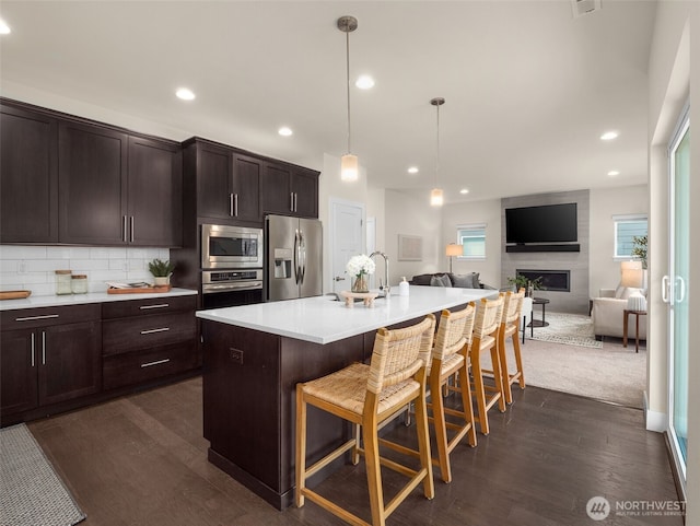 4419 141st Pl SE, Snohomish, WA 98296 - kitchen with appliances with stainless steel finishes, dark wood-type flooring, dark brown cabinets, a kitchen breakfast bar, and recessed lighting