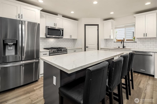 830 Mill Ave, Snohomish, WA 98290 - kitchen featuring appliances with stainless steel finishes, a breakfast bar area, white cabinetry, a kitchen island, and light stone countertops