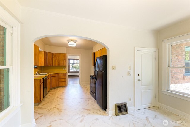 314 E 2nd St, Port Angeles, WA 98362 - kitchen featuring brown cabinets, black appliances, light countertops, arched walkways, and crown molding