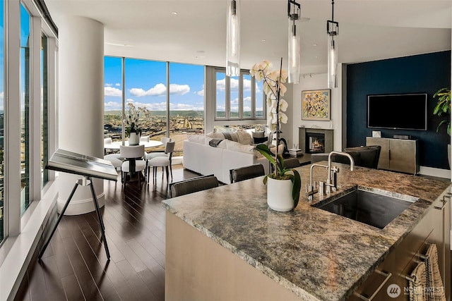 1521 2nd Ave Unit 3801, Seattle, WA 98101 - kitchen featuring open floor plan, dark wood-style flooring, dark stone counters, a warm lit fireplace, and floor to ceiling windows