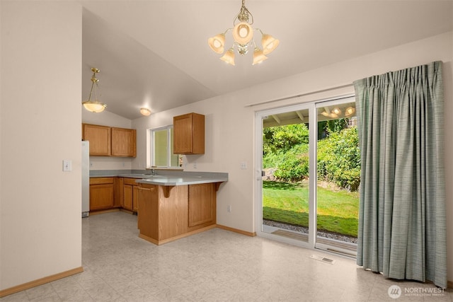 4050 NE 197th St, Lake Forest Park, WA 98155 - kitchen with freestanding refrigerator, a chandelier, brown cabinetry, a peninsula, and vaulted ceiling