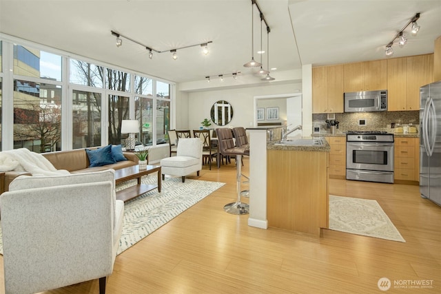 17 W Mercer St Unit 212, Seattle, WA 98119 - kitchen with appliances with stainless steel finishes, track lighting, light brown cabinetry, a breakfast bar area, and open floor plan