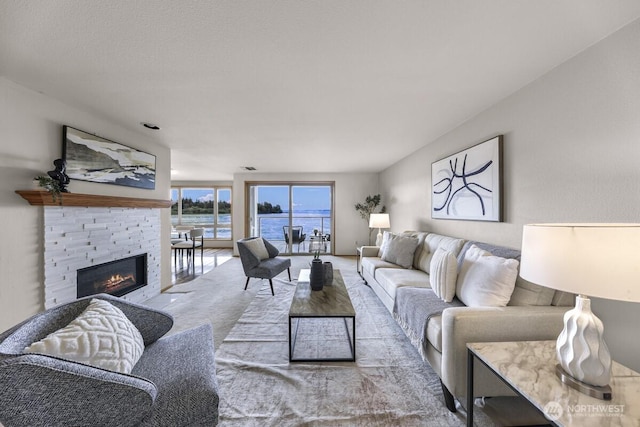 9727 NE Juanita Dr Unit 308, Kirkland, WA 98034 - living area featuring carpet flooring, a water view, and a stone fireplace