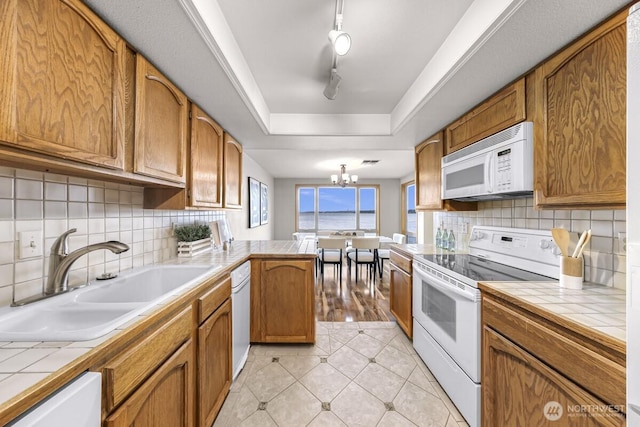 9727 NE Juanita Dr Unit 308, Kirkland, WA 98034 - kitchen featuring white appliances, tile counters, a chandelier, a peninsula, and brown cabinetry