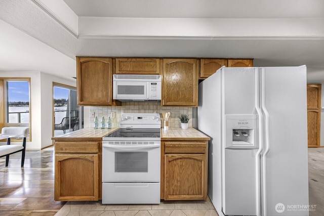 9727 NE Juanita Dr Unit 308, Kirkland, WA 98034 - kitchen with white appliances, tile countertops, tasteful backsplash, and brown cabinetry
