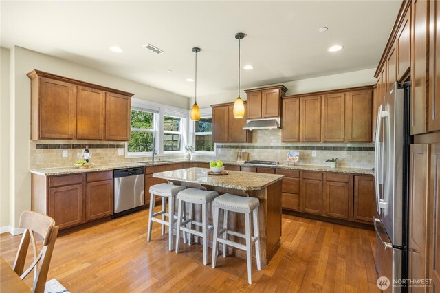 1501 209th Ave NE, Sammamish, WA 98074 - kitchen with appliances with stainless steel finishes, brown cabinets, under cabinet range hood, light wood finished floors, and recessed lighting