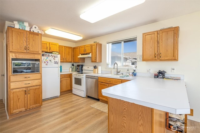 4421 Sucia Dr, Ferndale, WA 98248 - kitchen featuring white appliances, a peninsula, under cabinet range hood, light countertops, and light wood-style floors