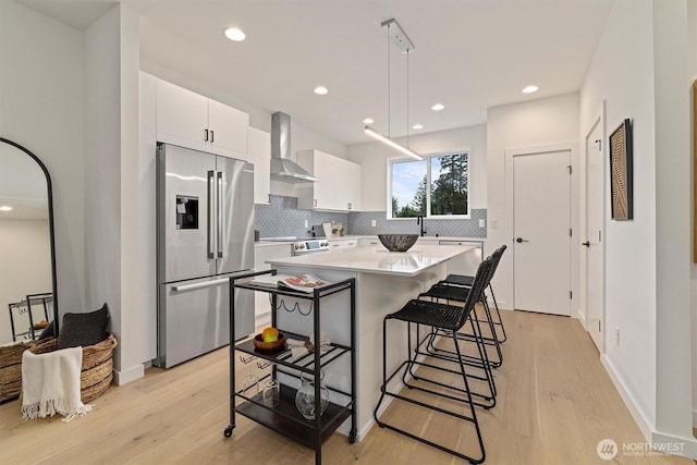 1323 N 185th St Unit A, Shoreline, WA 98133 - kitchen with stainless steel appliances, decorative backsplash, wall chimney range hood, light countertops, and light wood finished floors