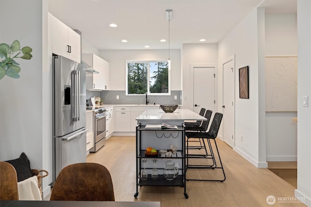 1323 N 185th St Unit A, Shoreline, WA 98133 - kitchen with appliances with stainless steel finishes, light wood-style floors, white cabinetry, backsplash, and recessed lighting