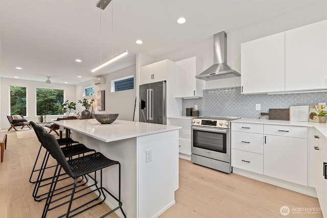 1323 N 185th St Unit A, Shoreline, WA 98133 - kitchen featuring appliances with stainless steel finishes, wall chimney range hood, a breakfast bar area, open floor plan, and light wood-style floors