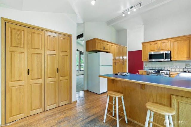 2417 179th Ave E, Lake Tapps, WA 98391 - kitchen featuring appliances with stainless steel finishes, decorative backsplash, a kitchen bar, light wood-type flooring, and a peninsula