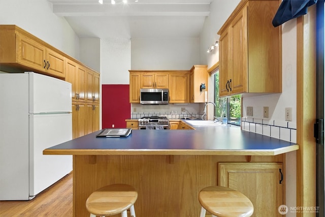 2417 179th Ave E, Lake Tapps, WA 98391 - kitchen with appliances with stainless steel finishes, a peninsula, light wood finished floors, a breakfast bar, and backsplash