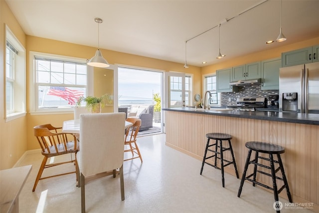 618 12th St, Bellingham, WA 98225 - kitchen featuring appliances with stainless steel finishes, under cabinet range hood, green cabinetry, dark countertops, and a kitchen bar