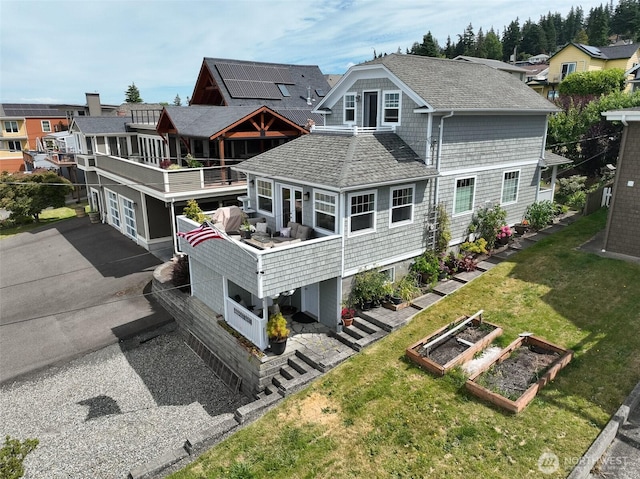 618 12th St, Bellingham, WA 98225 - rear view of property featuring a garden, driveway, roof with shingles, a lawn, and a balcony