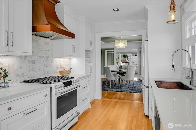 2456 4th Ave W, Seattle, WA 98119 - kitchen with custom range hood, white range with gas stovetop, white cabinetry, a chandelier, and light countertops