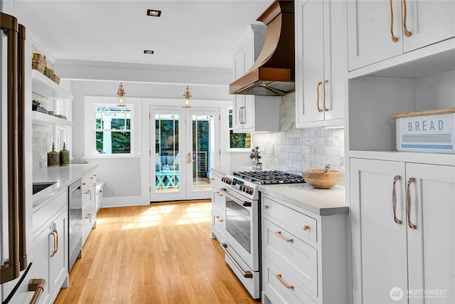 2456 4th Ave W, Seattle, WA 98119 - kitchen with high end stove, custom range hood, french doors, light countertops, and decorative backsplash