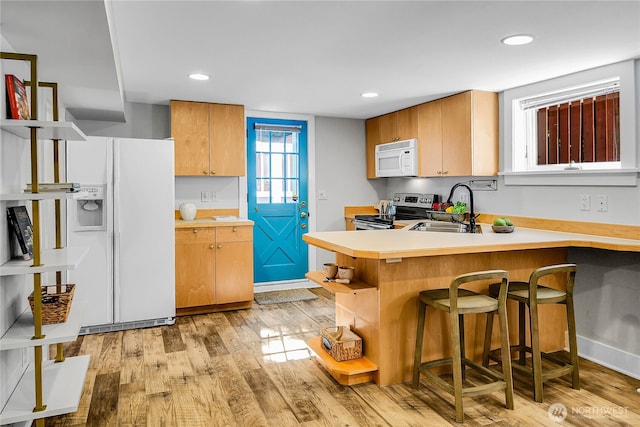 2456 4th Ave W, Seattle, WA 98119 - kitchen featuring white appliances, a peninsula, light wood-style flooring, light countertops, and a breakfast bar area