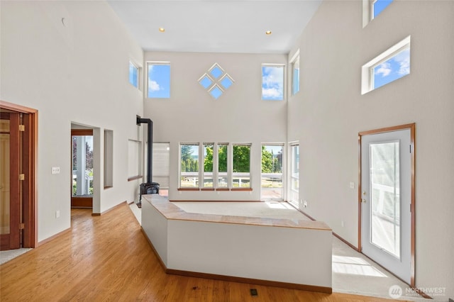 5225 Illahee Ln NE, Olympia, WA 98516 - unfurnished living room featuring a wood stove, a high ceiling, plenty of natural light, and light wood-type flooring
