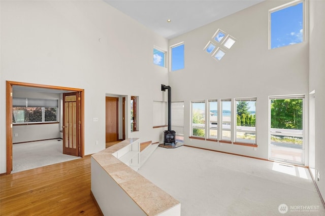 5225 Illahee Ln NE, Olympia, WA 98516 - unfurnished living room with a wood stove, a high ceiling, wood finished floors, and carpet floors