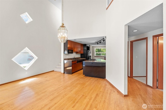 5225 Illahee Ln NE, Olympia, WA 98516 - kitchen with light wood-style flooring, a chandelier, pendant lighting, dark countertops, and freestanding refrigerator