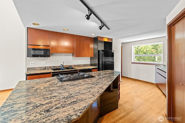 5225 Illahee Ln NE, Olympia, WA 98516 - kitchen with black appliances, a textured ceiling, track lighting, light wood-type flooring, and dark stone counters
