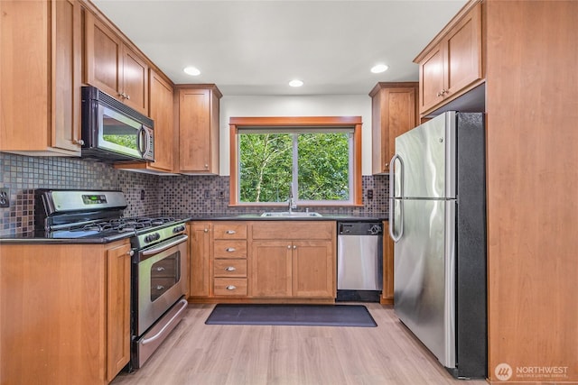 2511 NE 125th St Unit A, Seattle, WA 98125 - kitchen featuring appliances with stainless steel finishes, dark countertops, light wood-style flooring, and recessed lighting