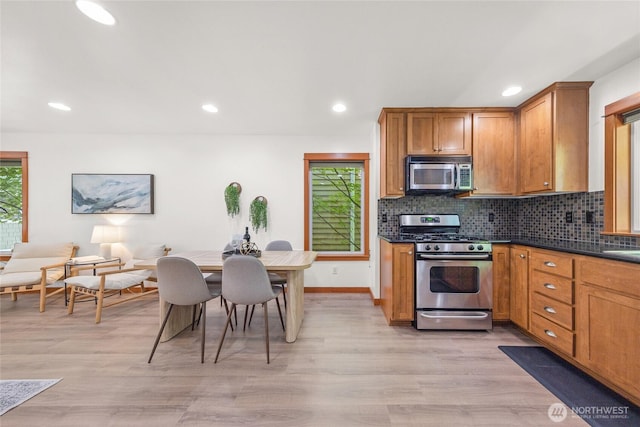 2511 NE 125th St Unit A, Seattle, WA 98125 - kitchen featuring appliances with stainless steel finishes, dark countertops, light wood-style floors, brown cabinets, and recessed lighting
