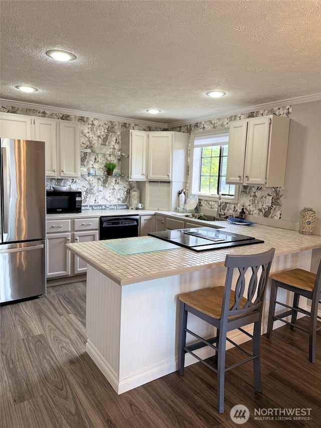 598 Blue Wing Loop SE, Ocean Shores, WA 98569 - kitchen with black appliances, a textured ceiling, dark wood-style flooring, light countertops, and a peninsula