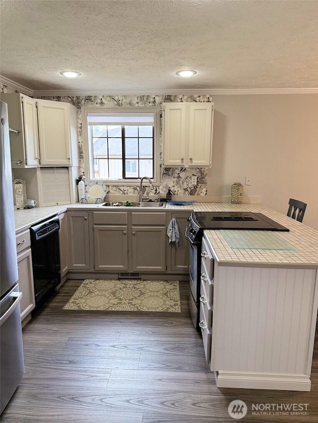 598 Blue Wing Loop SE, Ocean Shores, WA 98569 - kitchen with black dishwasher, a peninsula, a textured ceiling, freestanding refrigerator, and light countertops