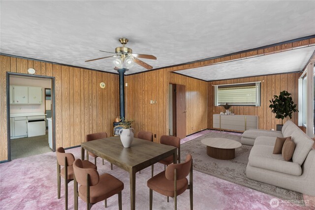 2507 Bay Ave, Hoquiam, WA 98550 - carpeted dining area with a wood stove, wooden walls, and a ceiling fan