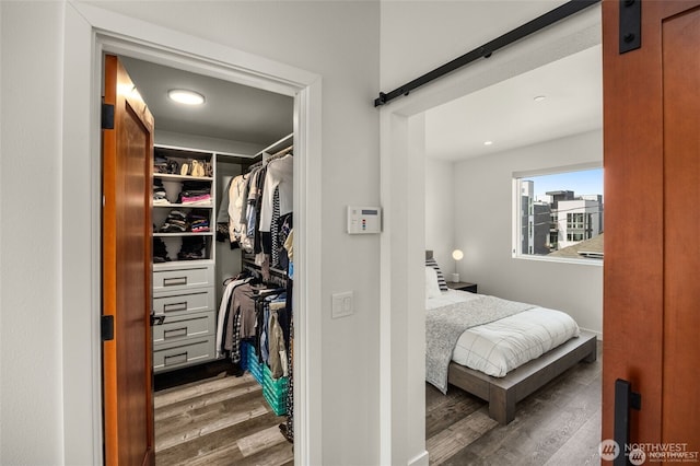 917 NW 51st St Unit D, Seattle, WA 98107 - bedroom with a barn door, wood finished floors, a spacious closet, and recessed lighting