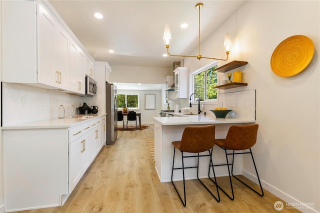 5310 46th Ave S, Seattle, WA 98118 - kitchen with stainless steel appliances, a kitchen breakfast bar, decorative backsplash, white cabinetry, and recessed lighting