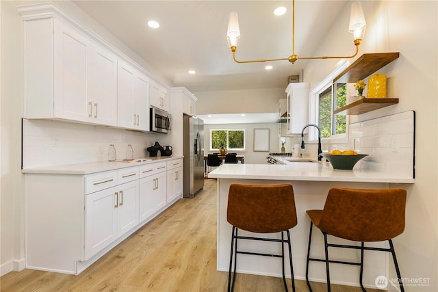 5310 46th Ave S, Seattle, WA 98118 - kitchen with appliances with stainless steel finishes, a peninsula, white cabinetry, decorative backsplash, and recessed lighting