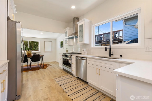 5310 46th Ave S, Seattle, WA 98118 - kitchen featuring appliances with stainless steel finishes, wall chimney range hood, decorative backsplash, white cabinetry, and light countertops