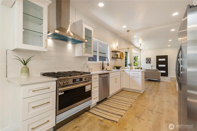 5310 46th Ave S, Seattle, WA 98118 - kitchen featuring wall chimney exhaust hood, stainless steel appliances, open floor plan, a peninsula, and light countertops
