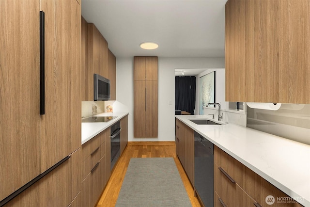 3650 26th Pl W Unit 202A, Seattle, WA 98199 - kitchen with modern cabinets, light countertops, light wood-style flooring, black appliances, and brown cabinets
