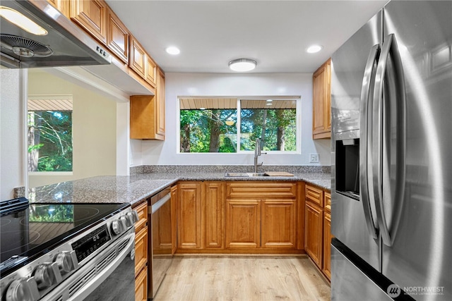 12621 SE 166th St, Renton, WA 98058 - kitchen featuring appliances with stainless steel finishes, ventilation hood, dark stone countertops, light wood-style flooring, and brown cabinets