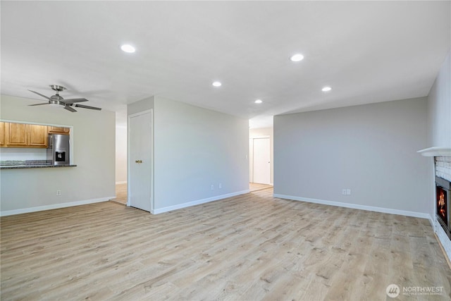 12621 SE 166th St, Renton, WA 98058 - unfurnished living room with a warm lit fireplace, recessed lighting, a ceiling fan, and light wood-style flooring