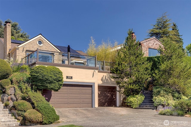 3006 43rd Ave W, Seattle, WA 98199 - view of front of property featuring a balcony, an attached garage, solar panels, stucco siding, and concrete driveway