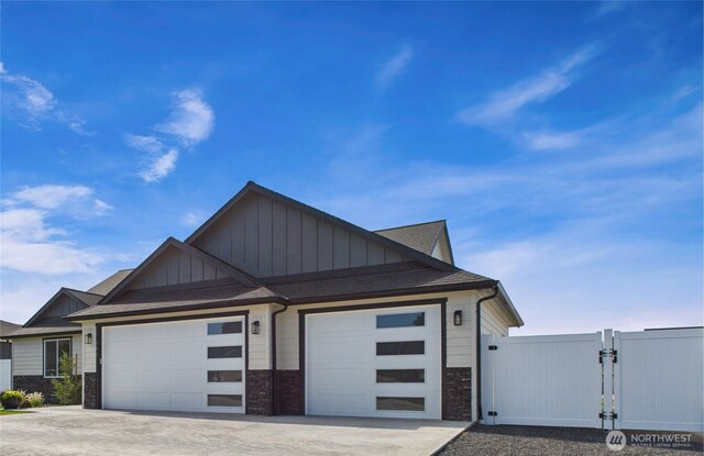 884 NE Tyler Pl E, Wenatchee, WA 98802 - view of front of home featuring board and batten siding, a gate, a garage, concrete driveway, and stone siding