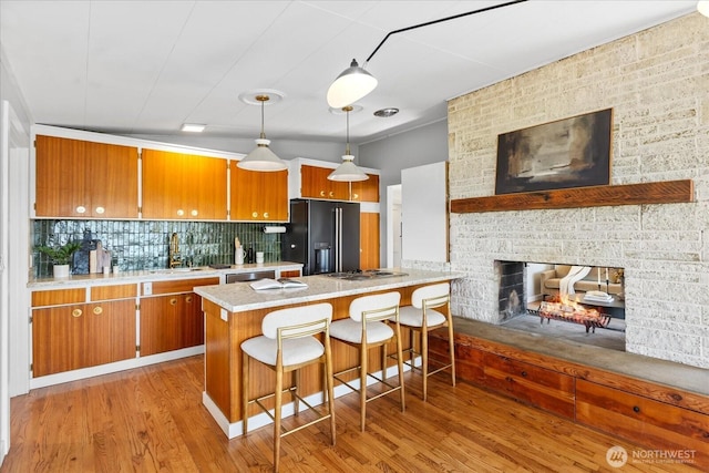 8733 21st Ave NW, Seattle, WA 98117 - kitchen featuring black fridge, brown cabinetry, light wood-style flooring, stainless steel dishwasher, and a peninsula